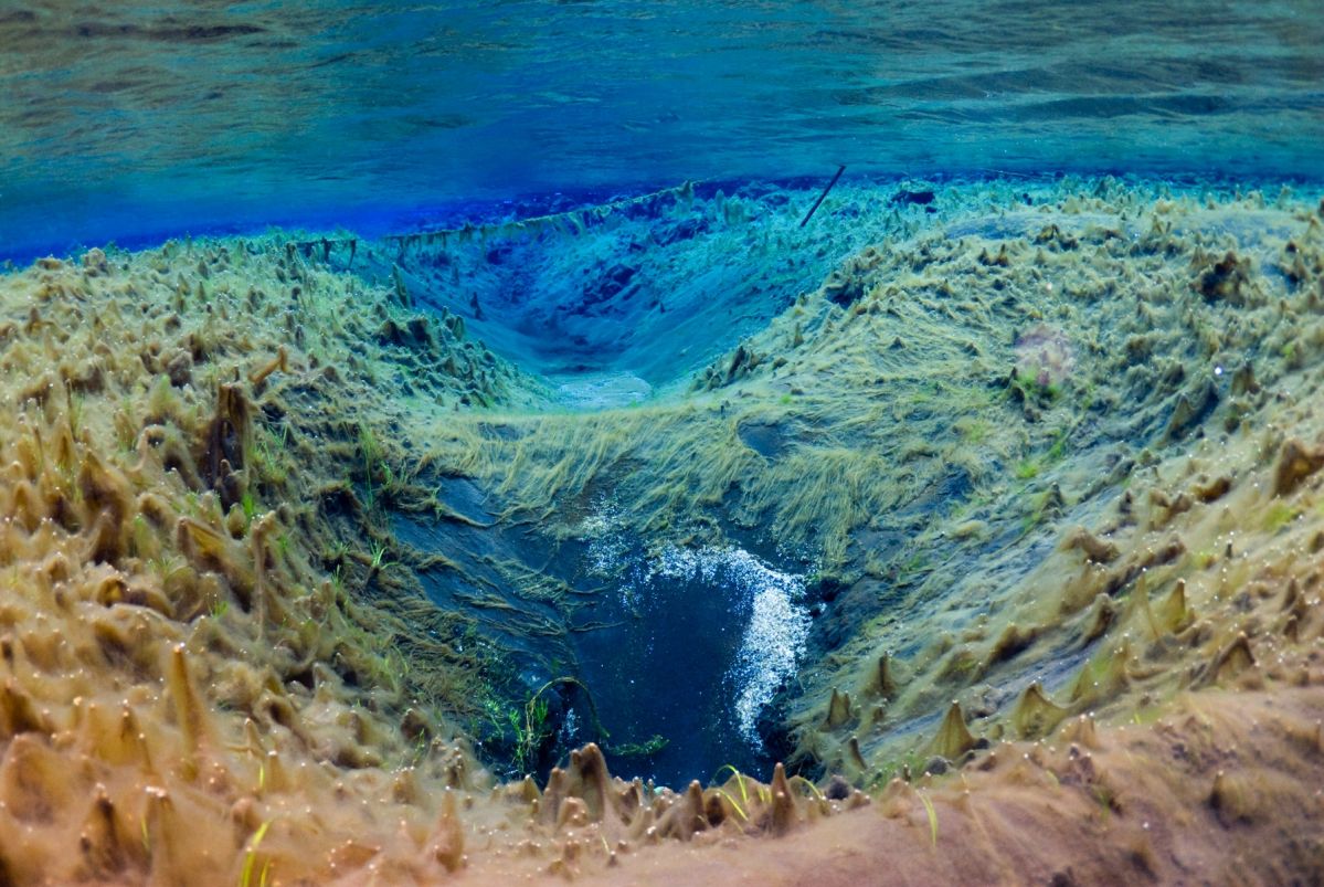 Underwater view of geothermal sediment in crystal clear water in River Litlaá.