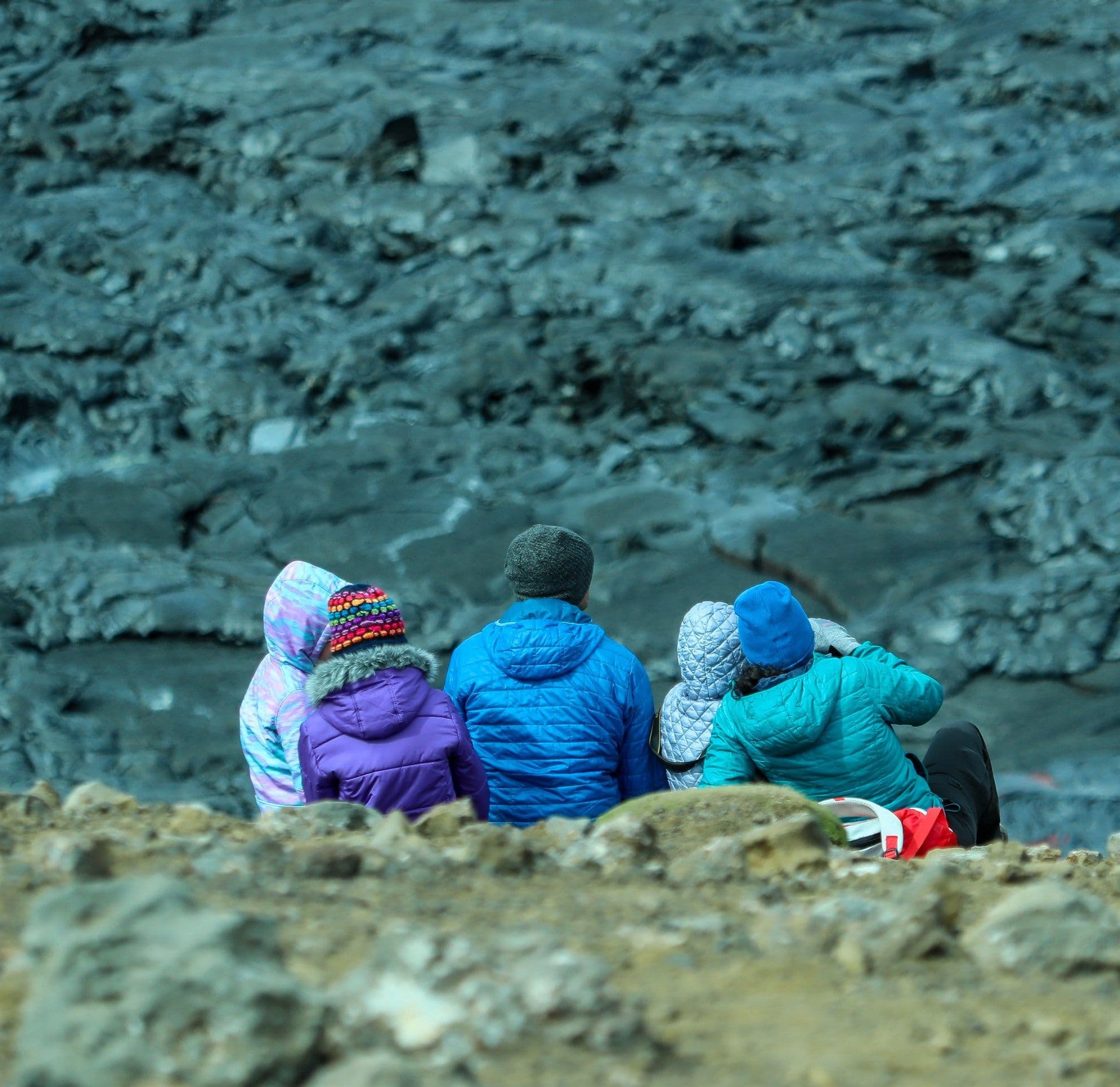Family with children sitting on lava field rocks in Iceland.