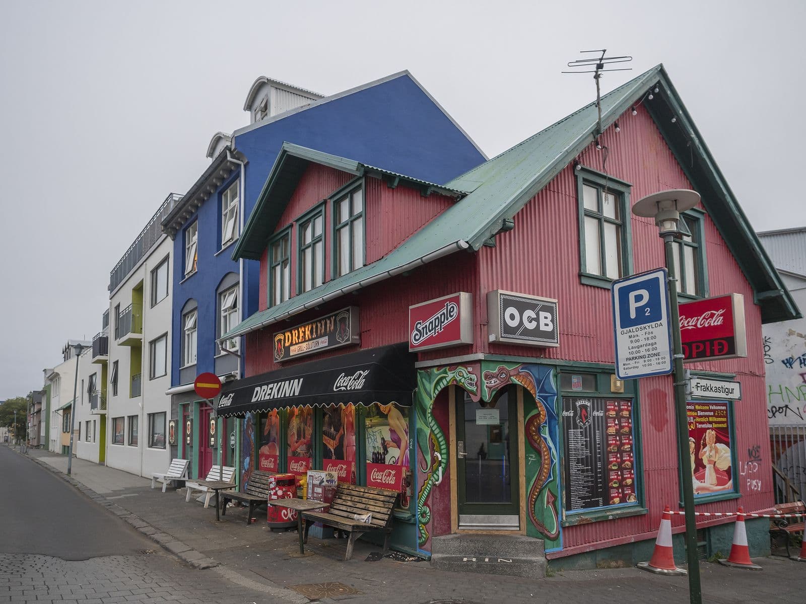 Street in Reykjavik center with an old historic pink sheet metal house fast food restaurant Drekinn.