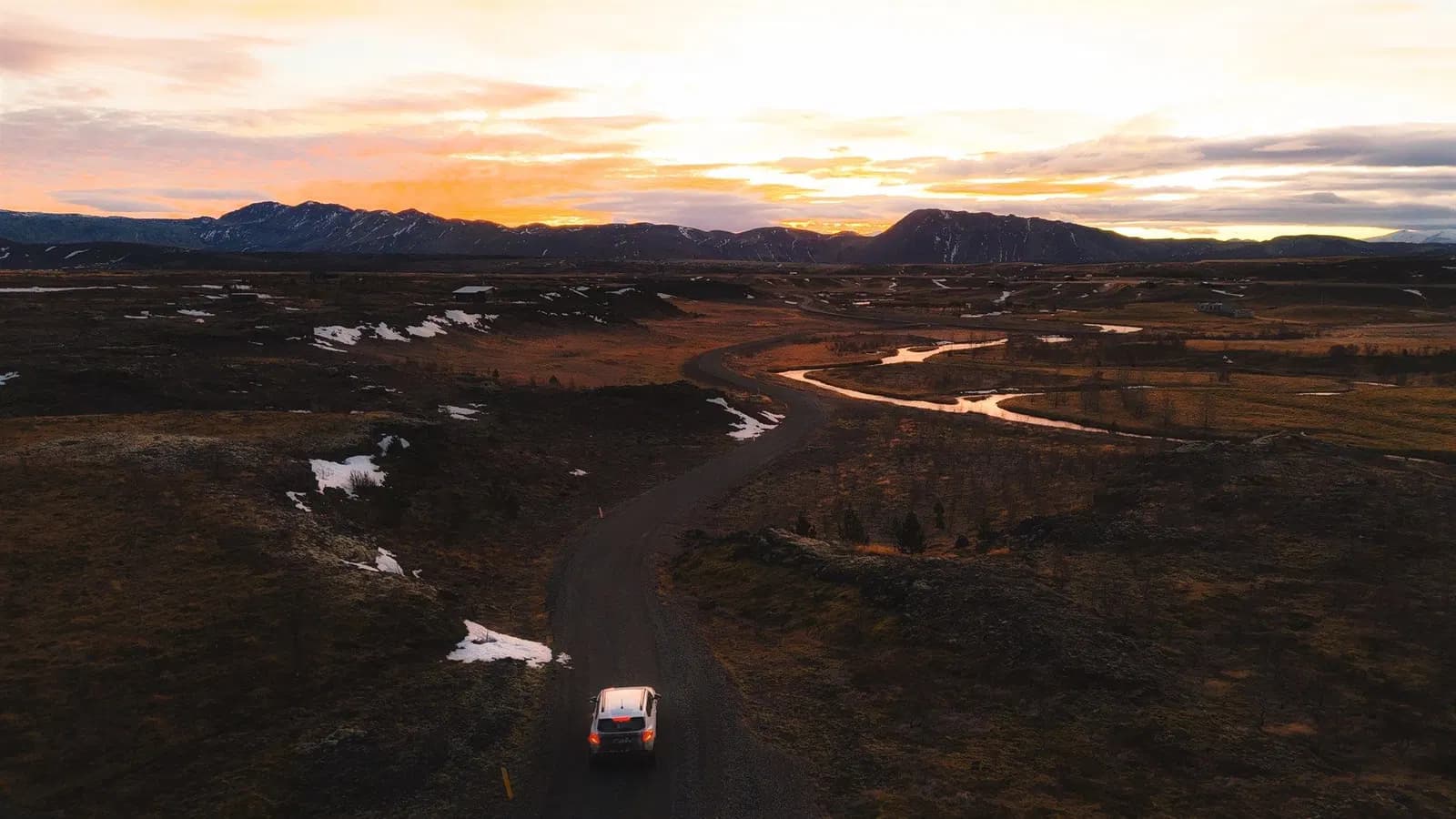 Rental car driving an empty road in Iceland at sunset