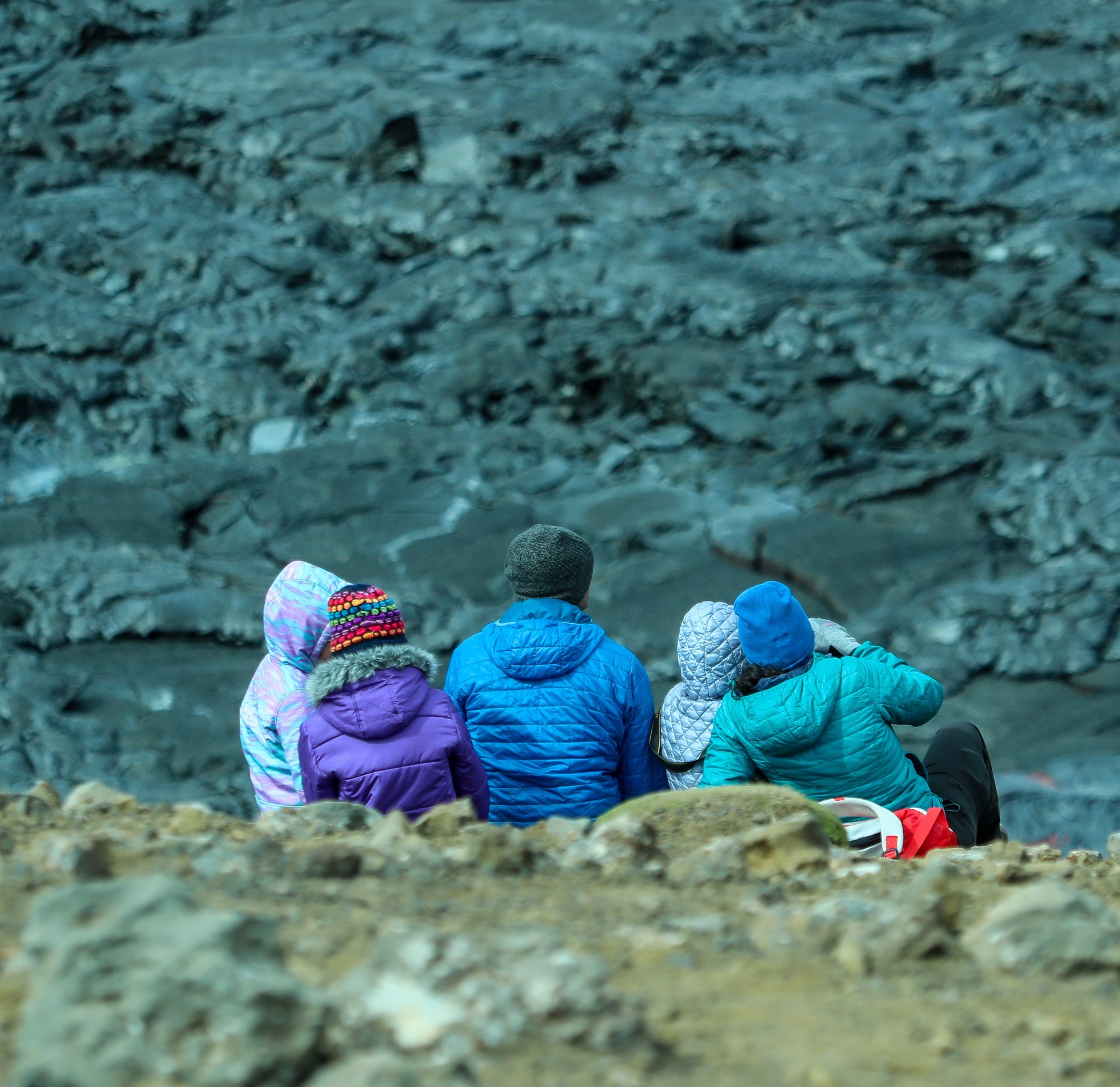 Family with children sitting on lava field rocks in Iceland.