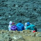 Family with children sitting on lava field rocks in Iceland.