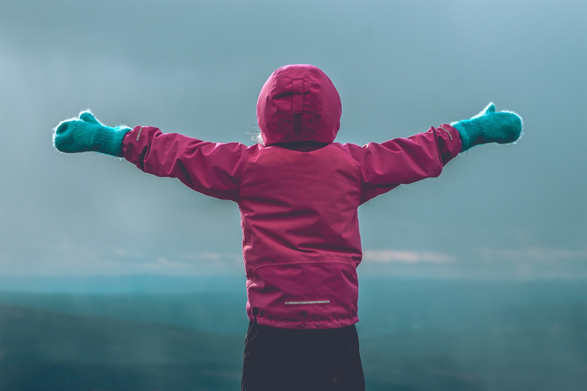 Child standing with arms out in front of Iceland landscape.