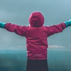 Child standing with arms out in front of Iceland landscape.