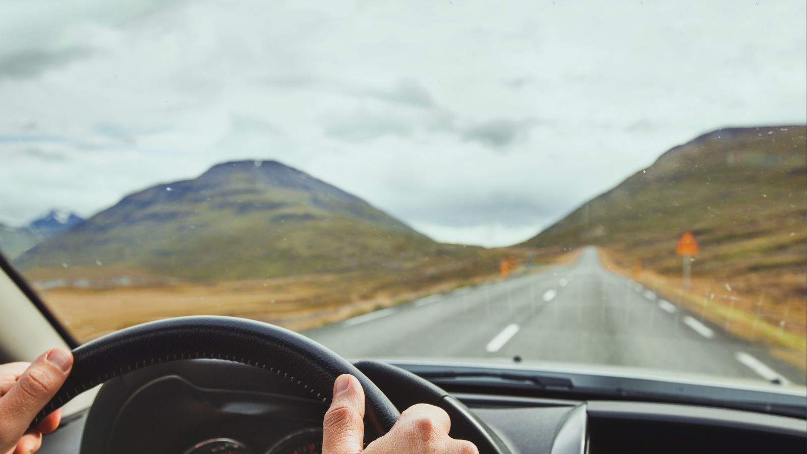 Person’s hands on a steering wheel driving a car in Iceland.
