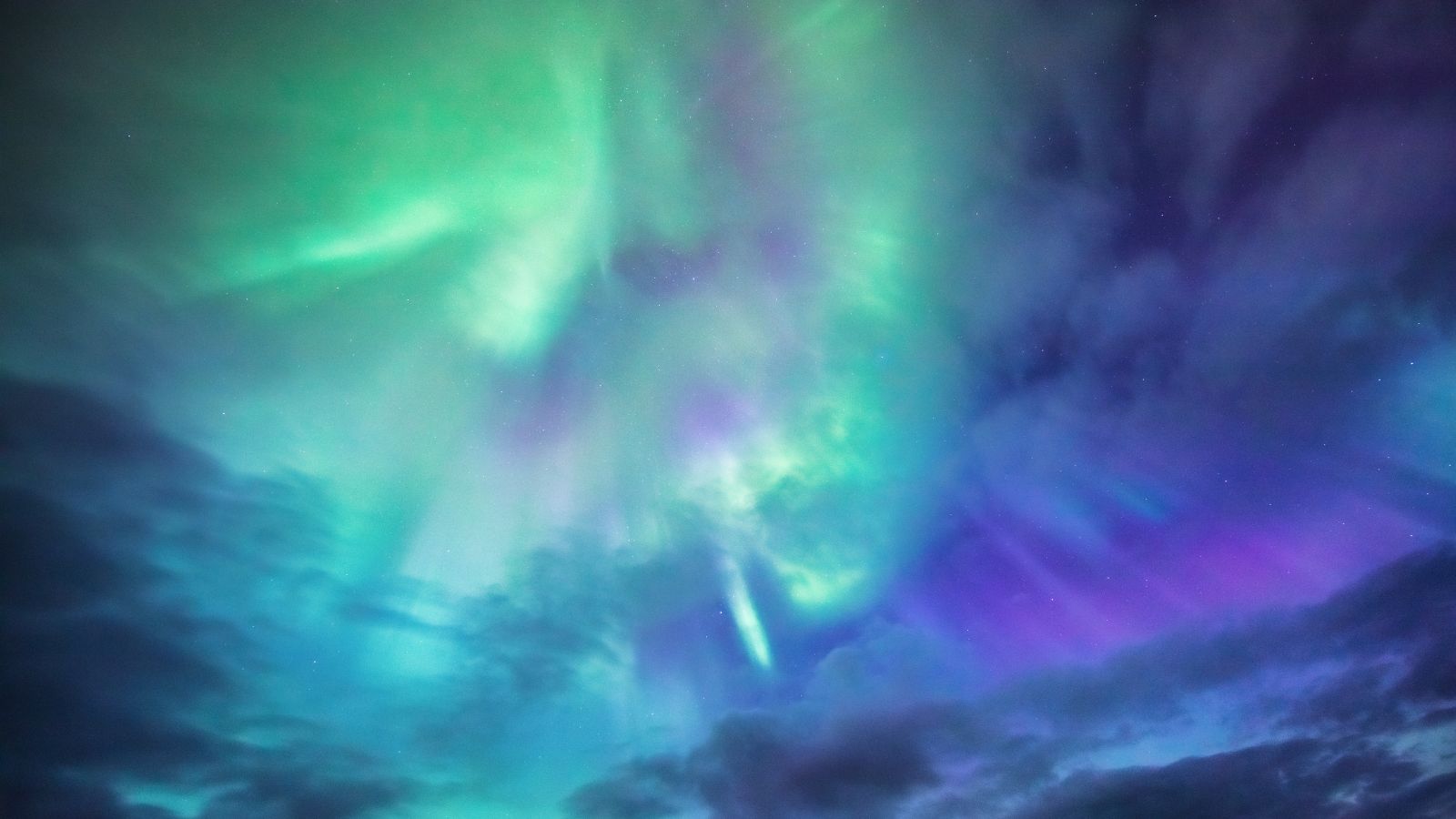 Green and purple Northern Lights lighting up the sky in Iceland.