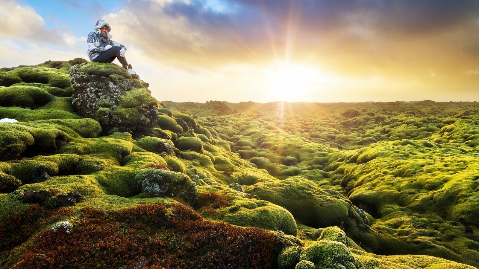Woman sitting on a rock overlooking Eldhraun lava field in Iceland.