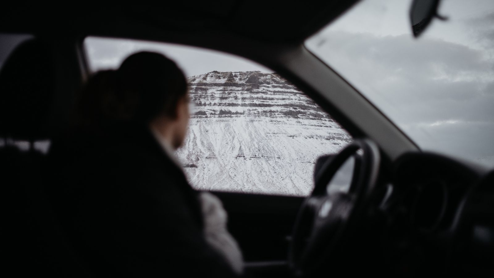 Person looking out a car window at Kirkjufell Mountain. 