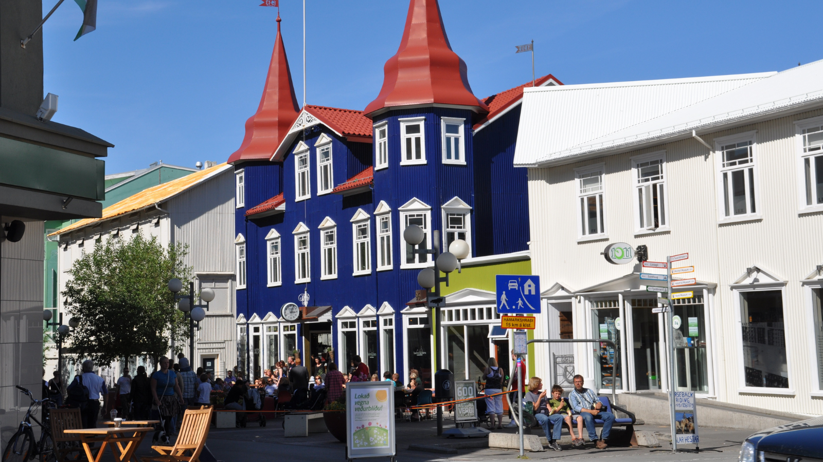 Blue building with red roof on a street in an Icelandic town.