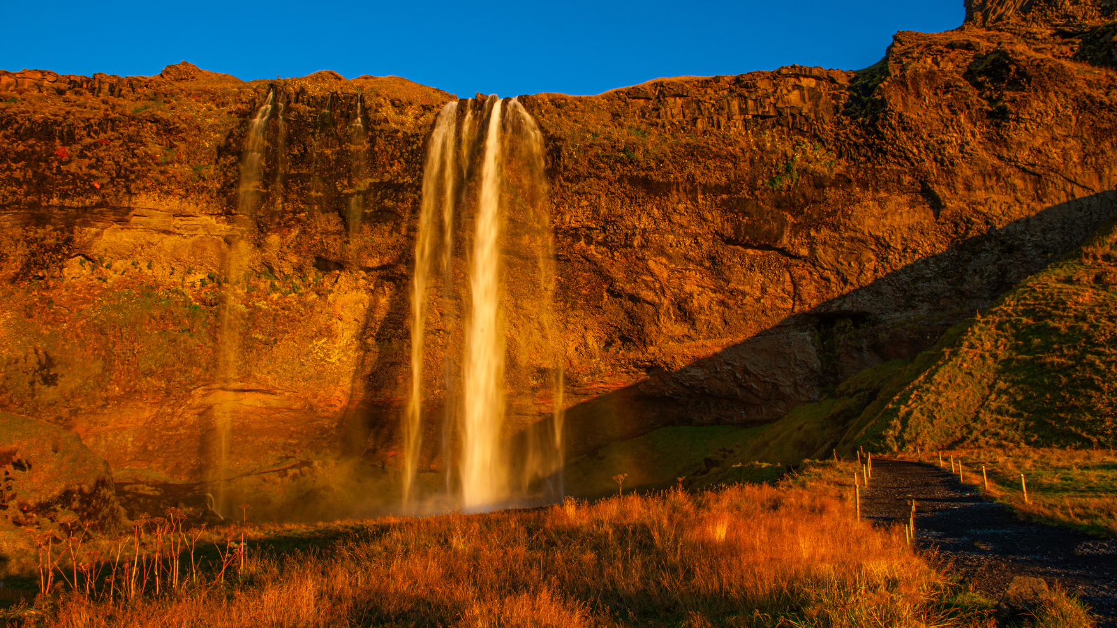 A waterfall in Iceland bathed in orange light with blue skies in Autumn.