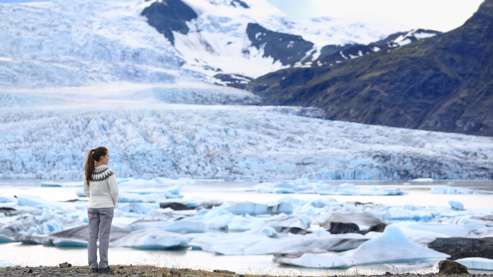 Woman standing in front of a snow-covered glacier in Iceland.