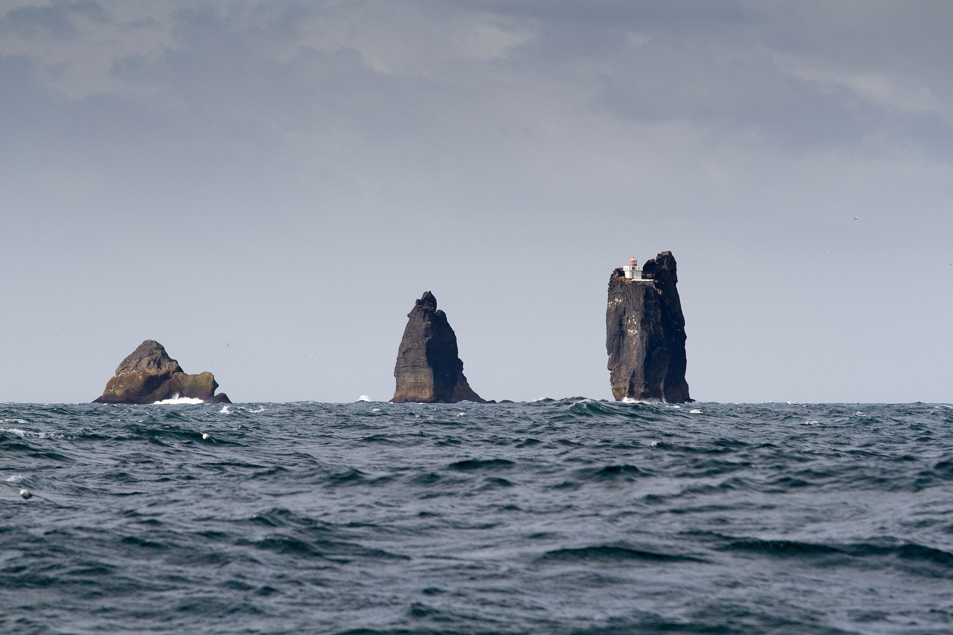 Þrídrangavit lighthouse from afar, sitting on a sea stack