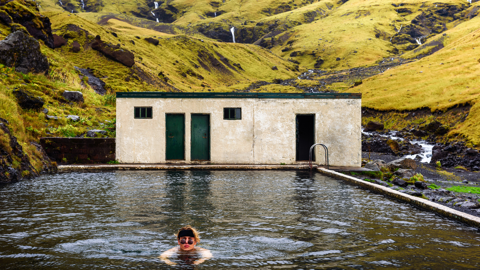 Young person swims in the Seljavallalaug Pool in South Iceland